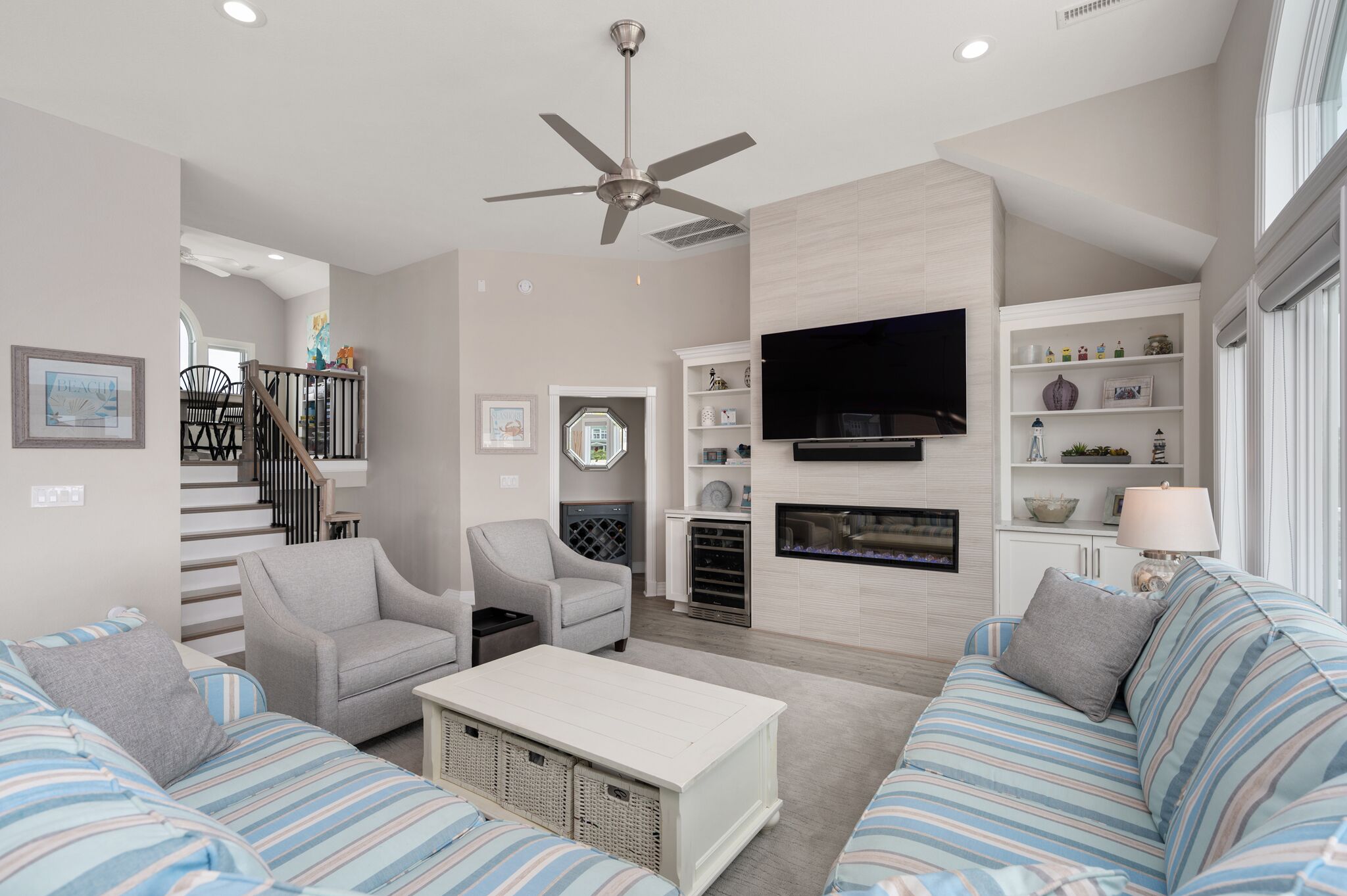 A modern living room with a fireplace, a flat-screen TV, and a ceiling fan.