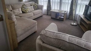 A living room with a sofa, a coffee table, and a television. - 3 Bedroom Ensuite Caravan (Shanklin)