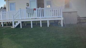 A mobile home with a deck, a garage, and a small porch area.