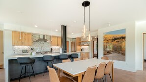 Una cocina moderna con una isla central, taburetes de bar y una mesa de comedor con sillas.
