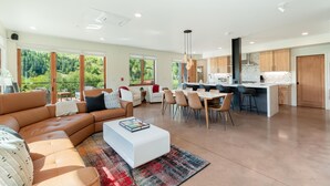 Amplia sala de estar con un sofá en forma de L, una mesa de comedor con sillas y una cocina con armarios de madera y una isla central.