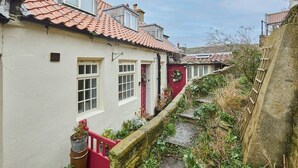 Un estrecho callejón con edificios tradicionales, una puerta roja y un muro de piedra.