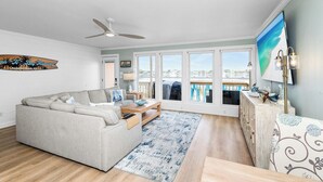 A living room with a sofa, coffee table, and a view of the city through large windows. - Bayfront Escape | Santa Rosa Sound Views | 100 Steps to the Beach! (Pensacola Beach)