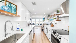 A modern kitchen with white cabinetry, stainless steel appliances, and a large island. - Bayfront Escape | Santa Rosa Sound Views | 100 Steps to the Beach! (Pensacola Beach)