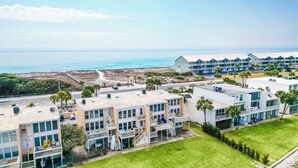 A coastal hotel with multiple buildings, balconies, and a view of the ocean.