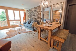 A spacious living area with a stone wall, a dining table, a sofa, and a large mirror. - Z Suite - Haus Roger (Zermatt)