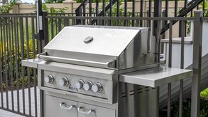 Een barbecue met een deksel, bedieningsknoppen en een handvat.