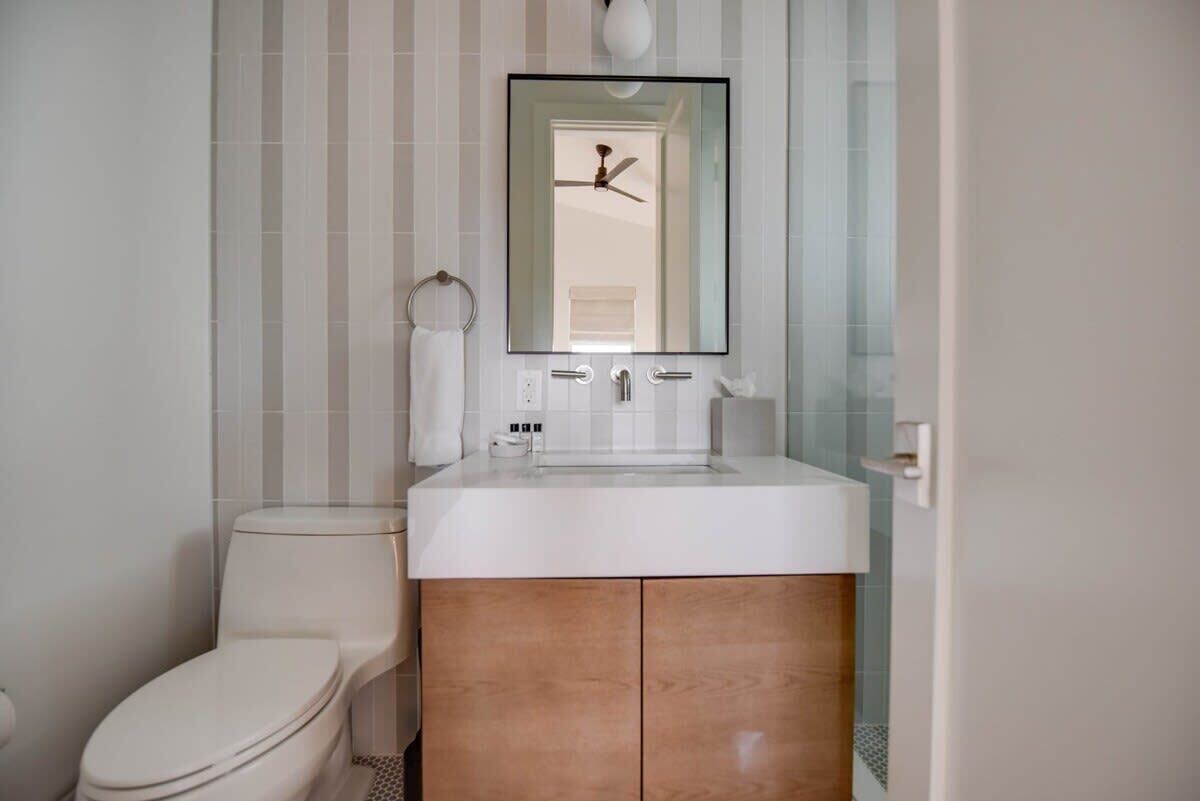 Une salle de bain comprenant des toilettes, un lavabo avec un miroir au-dessus et un porte-serviettes.