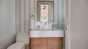 Une salle de bain comprenant des toilettes, un lavabo avec un miroir au-dessus et un porte-serviettes.