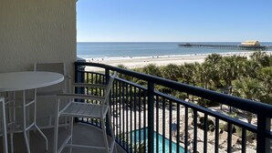 Un balcon avec piscine, vue sur la plage et un quai.