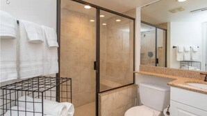Ein modernes Badezimmer mit einer Duschkabine aus Glas, einer weißen Toilette und einem Waschbecken auf einer Ablagefläche.