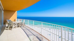 Ein Balkon mit Blick auf den Ozean, einem weißen Geländer und einem Tisch mit Stühlen.
