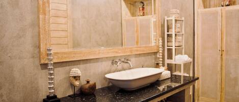 Une salle de bain avec un grand miroir, un lavabo blanc, un porte-serviettes et un meuble en bois.