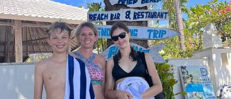 Señal de bienvenida con la leyenda 'Welcome Dhau Teya' y 'Amed Beach', que indica un complejo turístico en la playa.