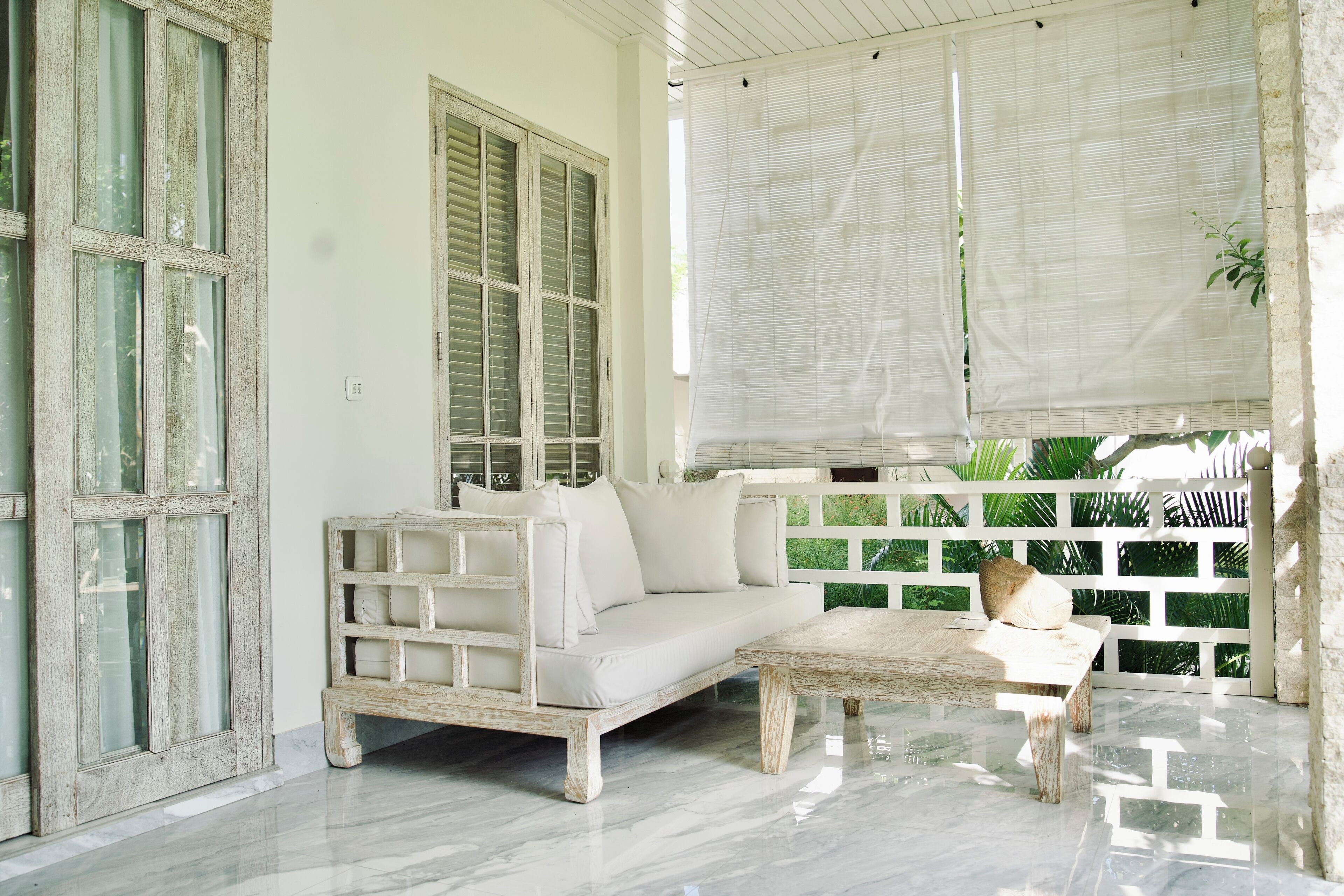 A room with a white sofa, a wooden coffee table, and a white railing.