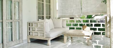 A room with a white sofa, a wooden coffee table, and a white railing.