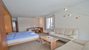 Une pièce de taille modeste comprenant un lit, un canapé, une petite table et un coin repas.