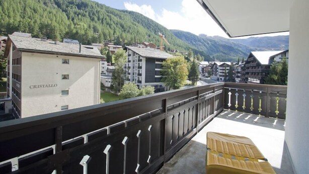 Un balcon avec vue sur une montagne et des bâtiments, dont un bâtiment portant l’inscription « CRISTALLO ».