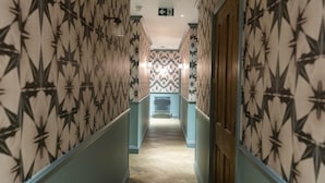 A hallway with patterned wallpaper, a radiator, and a wooden door. - THE KNIGHT OF NOTTINGHILL (London)