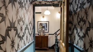 A hallway with patterned wallpaper, a wooden cabinet, a framed picture, and a staircase. - THE KNIGHT OF NOTTINGHILL (London)