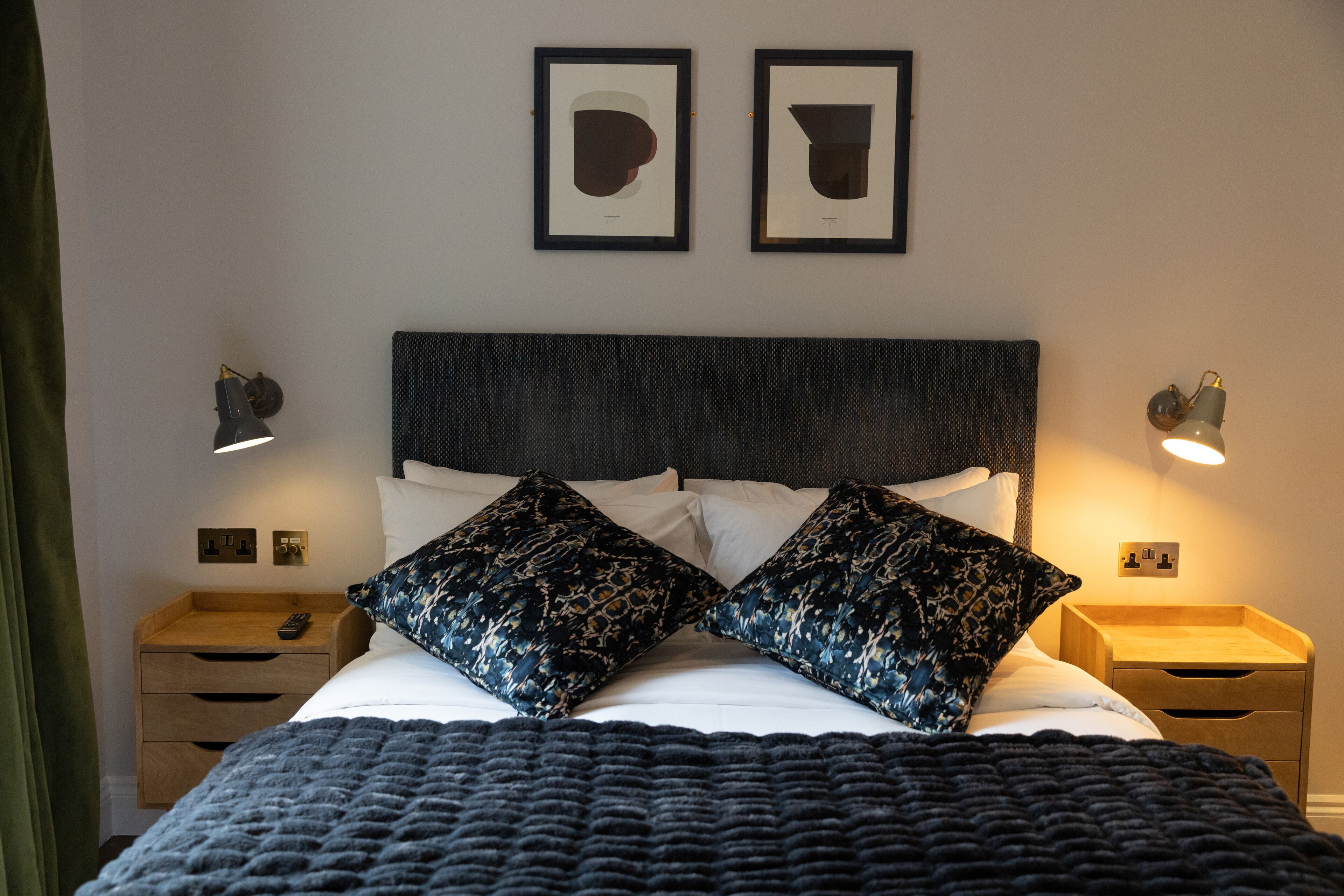 A neatly made bed with patterned pillows, a dark headboard, and bedside lamps.