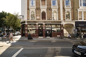 A street view of The Knight of Notting Hill, a building with a classic facade, a prominent entrance, and a signboard advertising its name. - THE KNIGHT OF NOTTINGHILL (London)