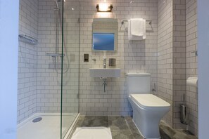 A modern bathroom with a glass-enclosed shower, a white sink, and a toilet. - THE KNIGHT OF NOTTINGHILL (London)