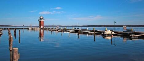 A calm waterfront with a lighthouse and wooden docks.