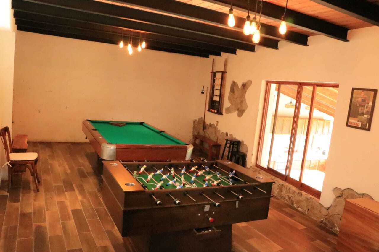Una habitació amb taula de futbolí, taula de billar i finestra amb vista.