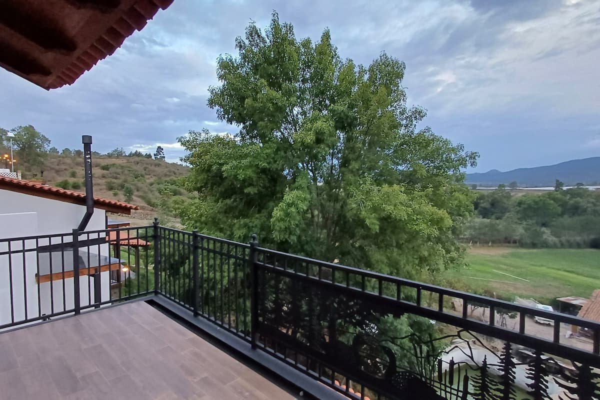 Un balcón con vistas a un árbol y un paisaje lejano.