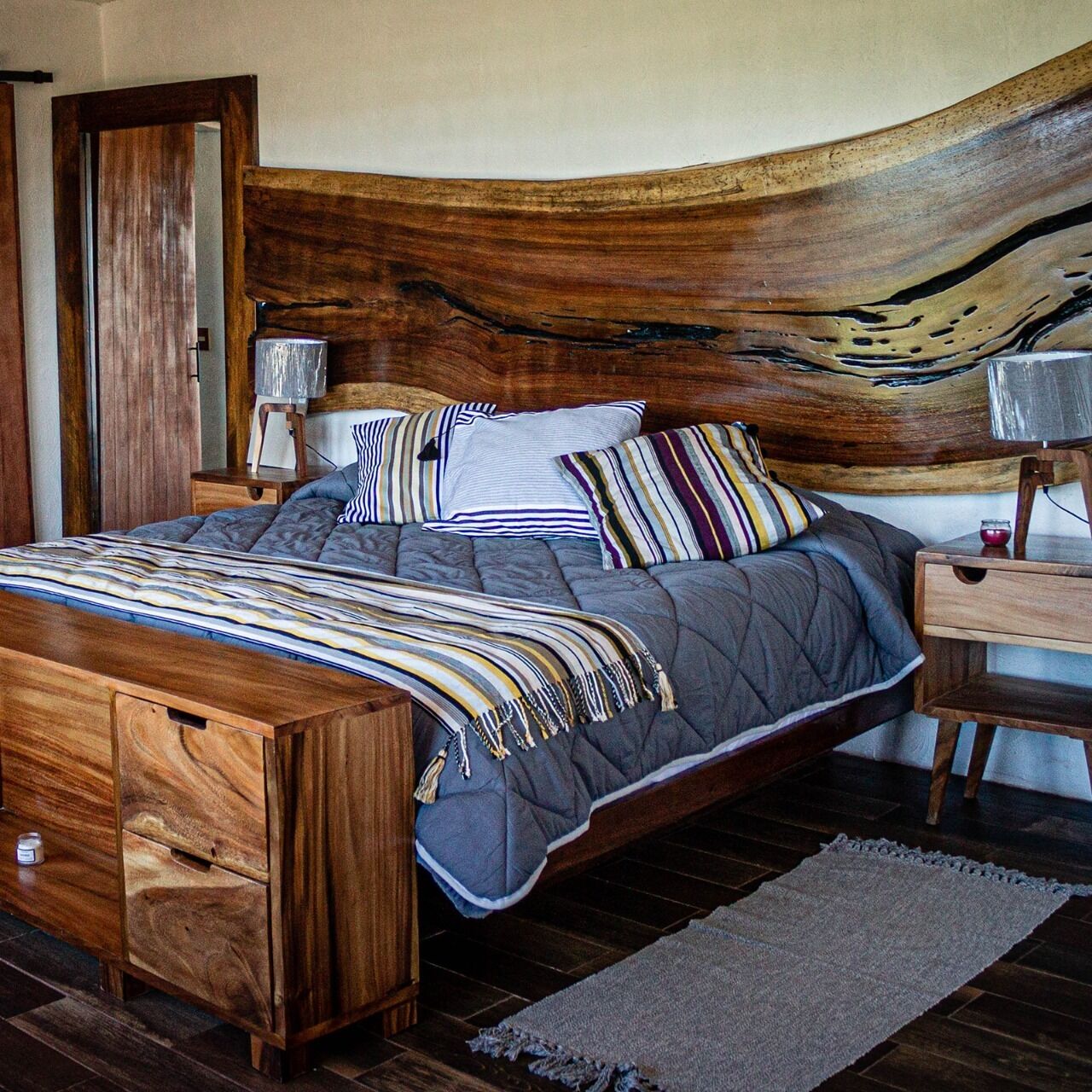 Una cama de madera con un cabecero único, una mesita de noche y un aparador de madera.