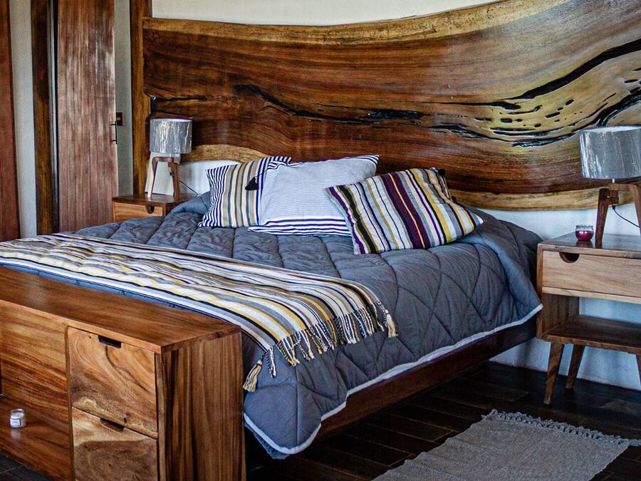 Una cama de madera con un cabecero único, una mesita de noche y un aparador de madera.