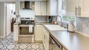 Una cocina con armarios blancos, estufa de acero inoxidable y salpicadero de azulejos.