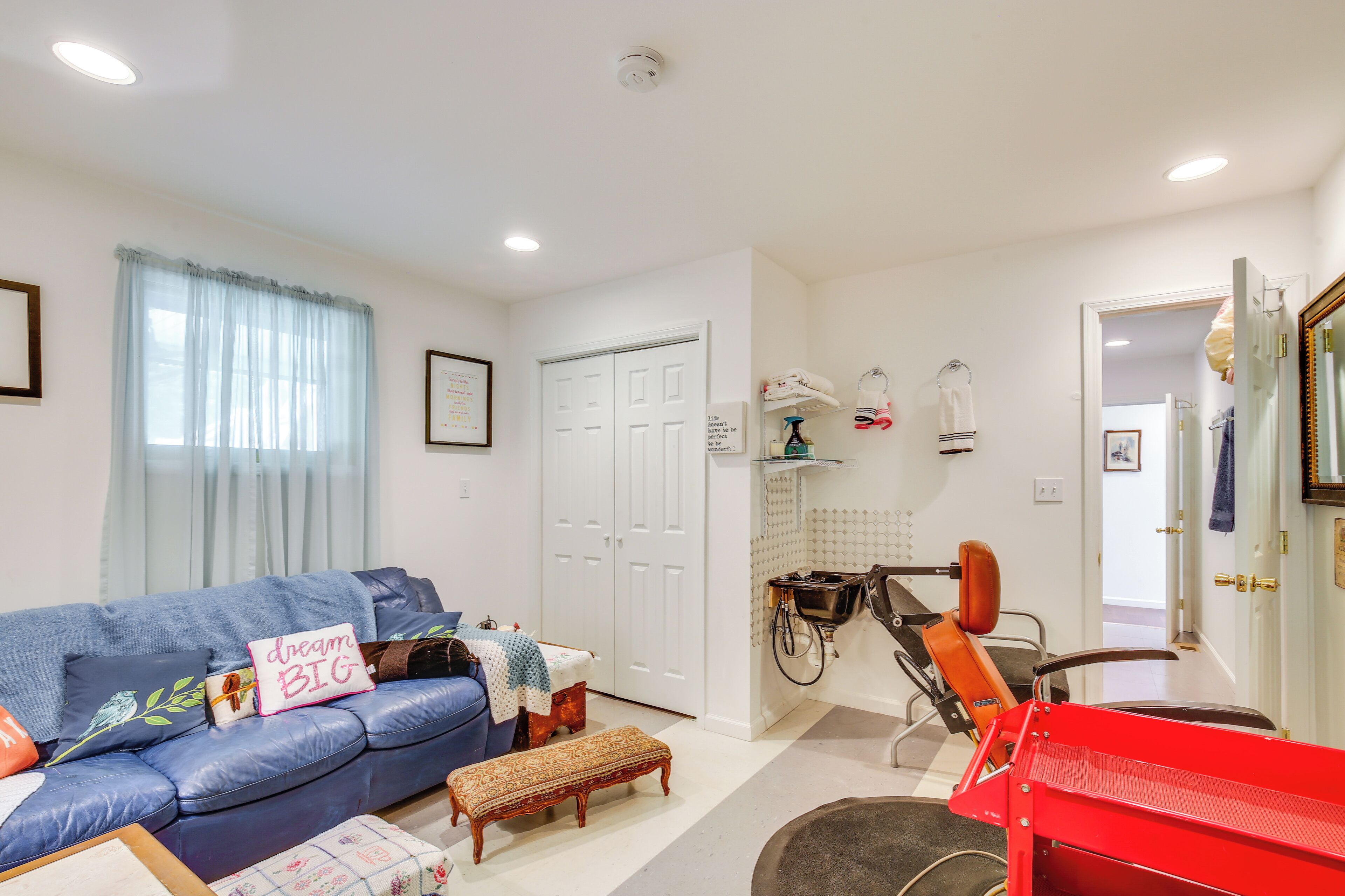A living room with a blue sofa, a small wooden bench, and a red exercise bike.