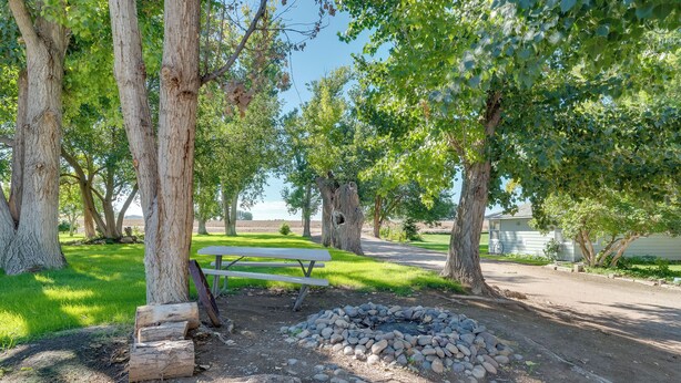 A picnic area with a fire pit, benches, and trees. - Cozy Idaho Retreat w/ Grill & Fire Pit! (Caldwell)