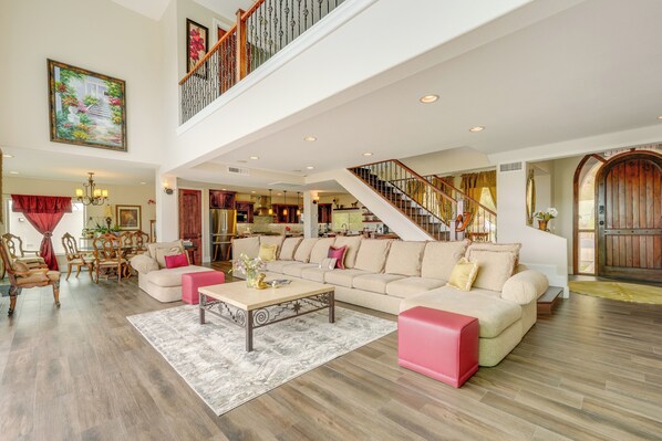 A spacious living area with a high ceiling, a staircase, and a dining area. - Group-friendly Desert Escape! Putting Green, Pool (Phoenix)