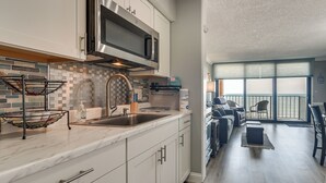 A modern kitchen with a microwave, sink, and tiled backsplash. - Pool Access: 8th-floor Condo on North Myrtle Beach (North Myrtle Beach)
