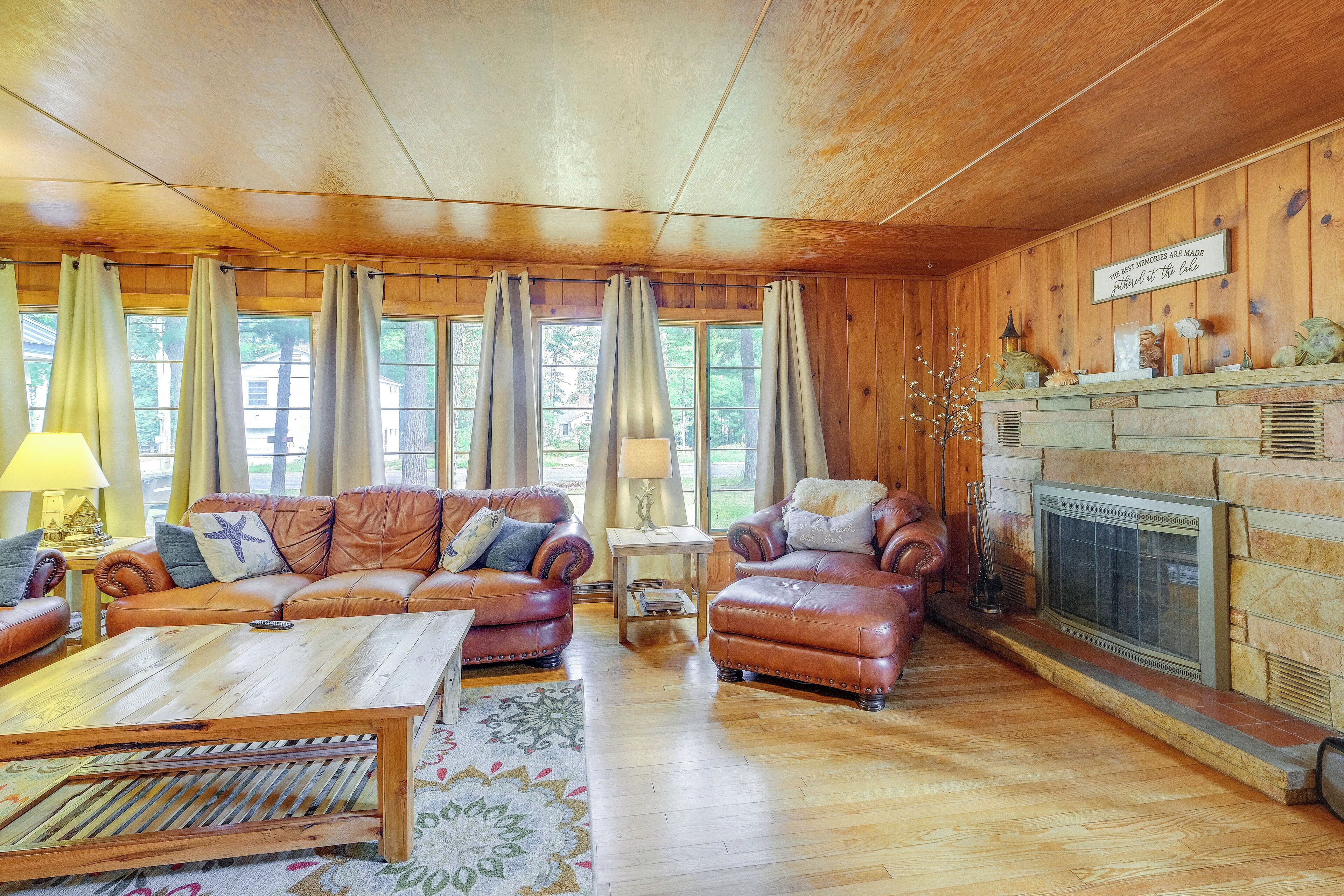 A cozy living room with wooden walls, a fireplace, leather sofas, and a coffee table.