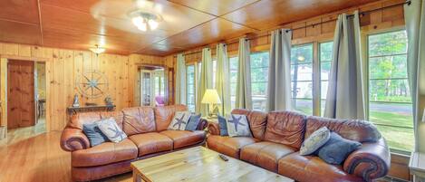 A cozy living room with a large brown leather sectional sofa, a wooden coffee table, and a wooden ceiling with a fan.