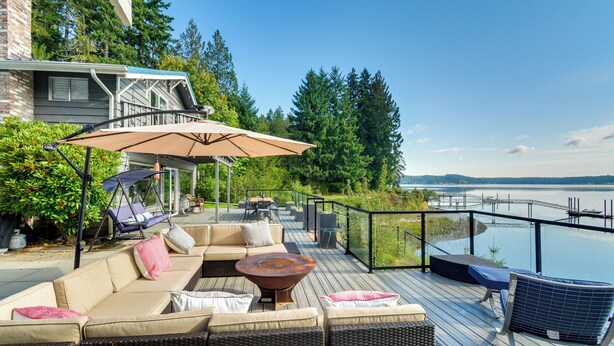 A deck with outdoor furniture, a swing chair, and a view of a body of water. - Waterfront Allyn Retreat w/ Guest House & Beach! (Allyn)