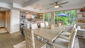 A modern kitchen with white cabinets, stainless steel appliances, and a dining area with a wooden table and wicker chairs. - Waterfront Allyn Retreat w/ Guest House & Beach! (Allyn)