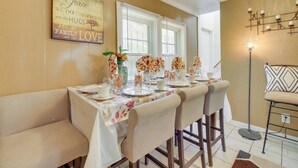 A dining area with a table set for four, a floral vase, and a wall with a family love sign.