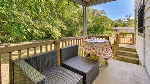 A covered patio with wicker furniture and a table with a floral tablecloth.