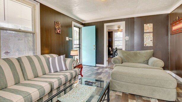 A living room with a striped sofa, a beige armchair, and a glass coffee table.