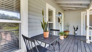 A covered porch with a table and chairs, potted plants, and a door leading to the interior.
