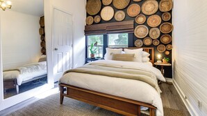 Een slaapkamer met een bed, een nachtkastje met een lamp en een wand versierd met gevlochten manden.