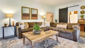 A living room with a sofa, coffee table, and a lamp. There are two paintings on the wall and a plant on the coffee table. - Fire Pit & Yard: Updated Winter Garden Home! (Winter Garden)