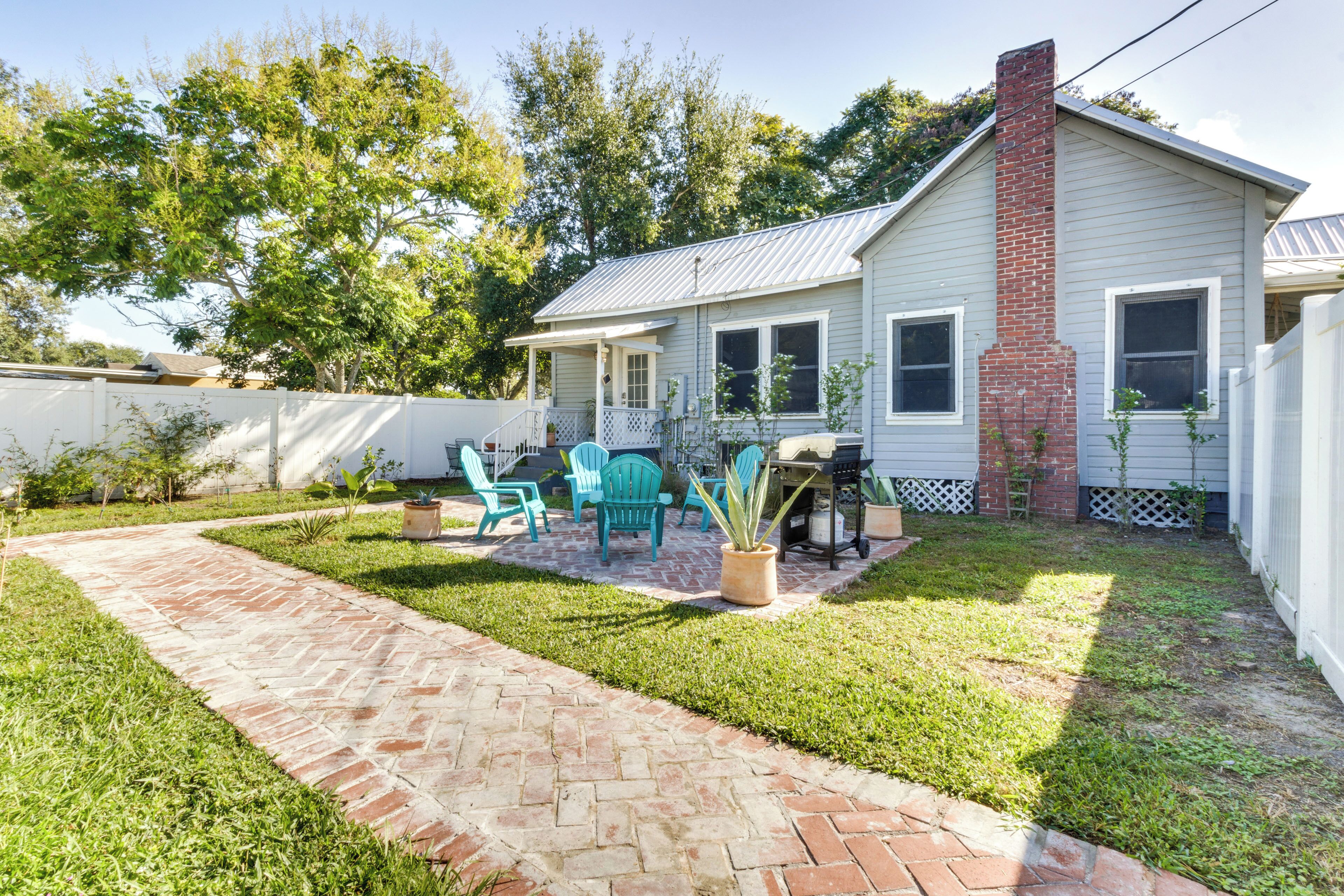 A house with a brick patio, outdoor seating, and a small garden.