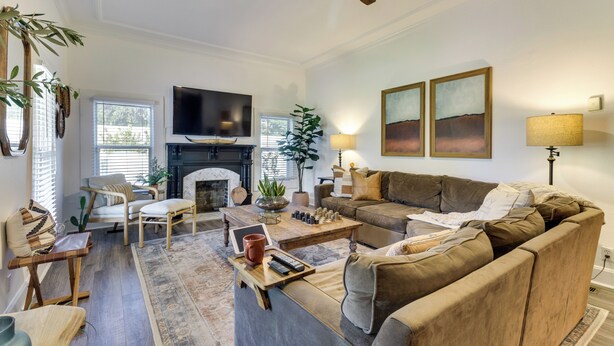 Een woonkamer met een open haard, een bank, fauteuils en een salontafel.