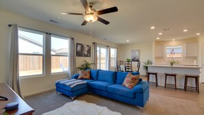 A living room with a blue sectional sofa, a white furry rug, and a ceiling fan. - Pet-friendly Merced Vacation Rental! (Merced)
